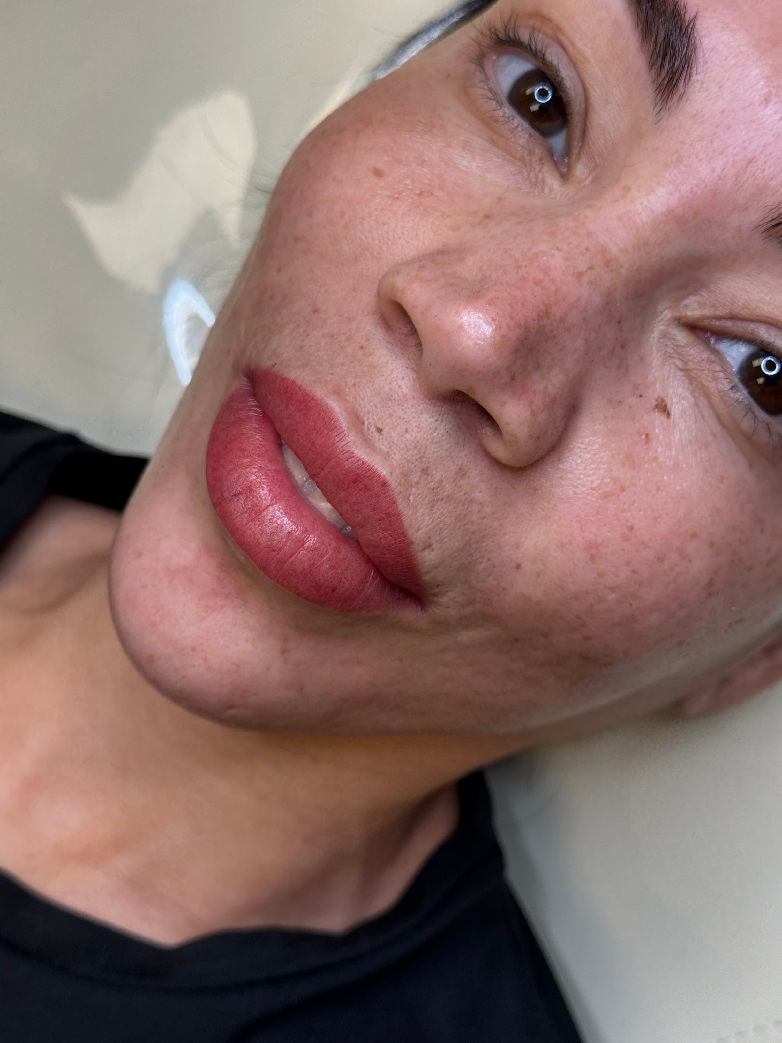 Healed lip blush in warm rose on freckled medium skin, client portrait looking up